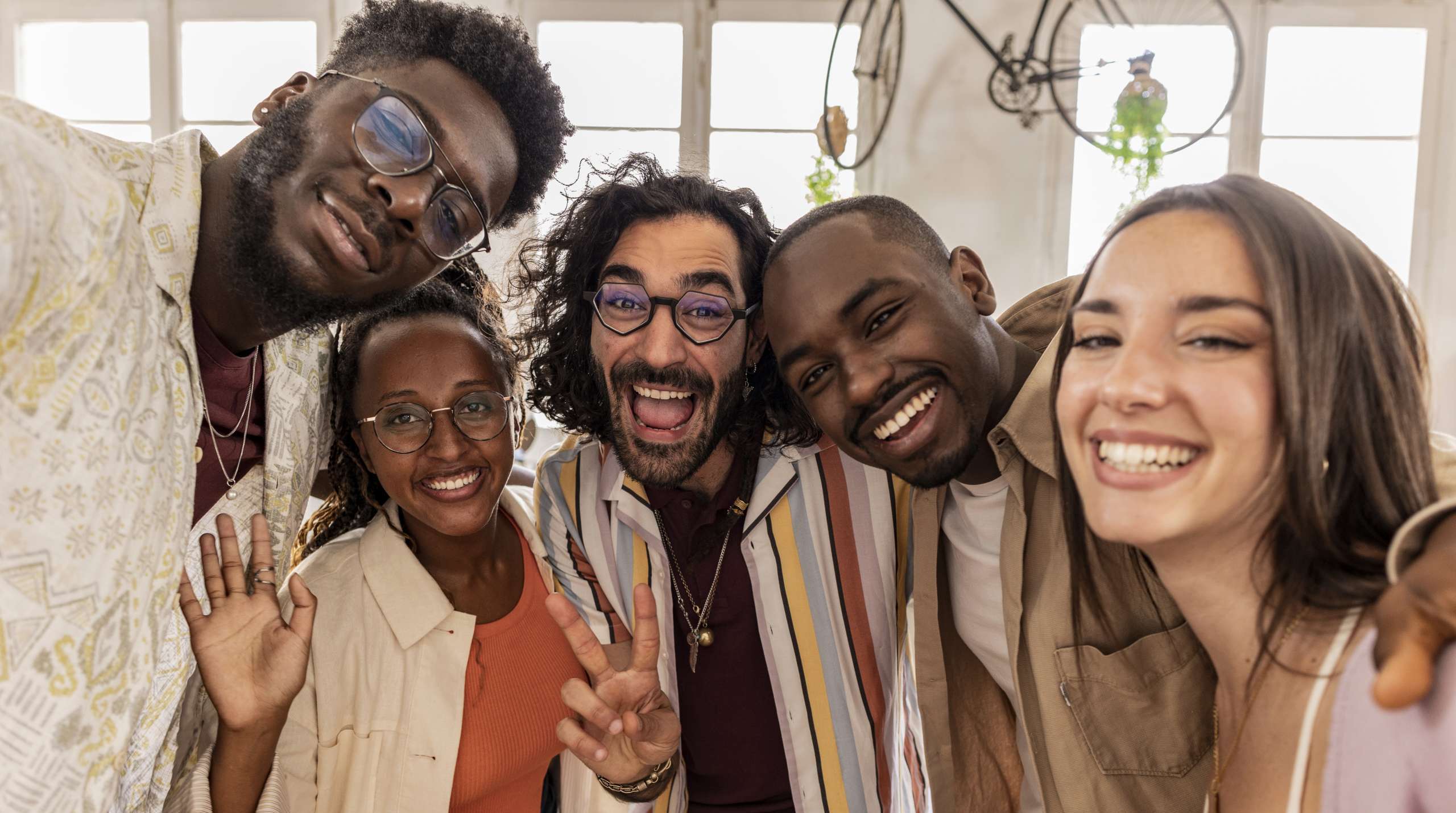 Group of smiling, diverse coworkers taking a cheerful selfie in a bright office setting
