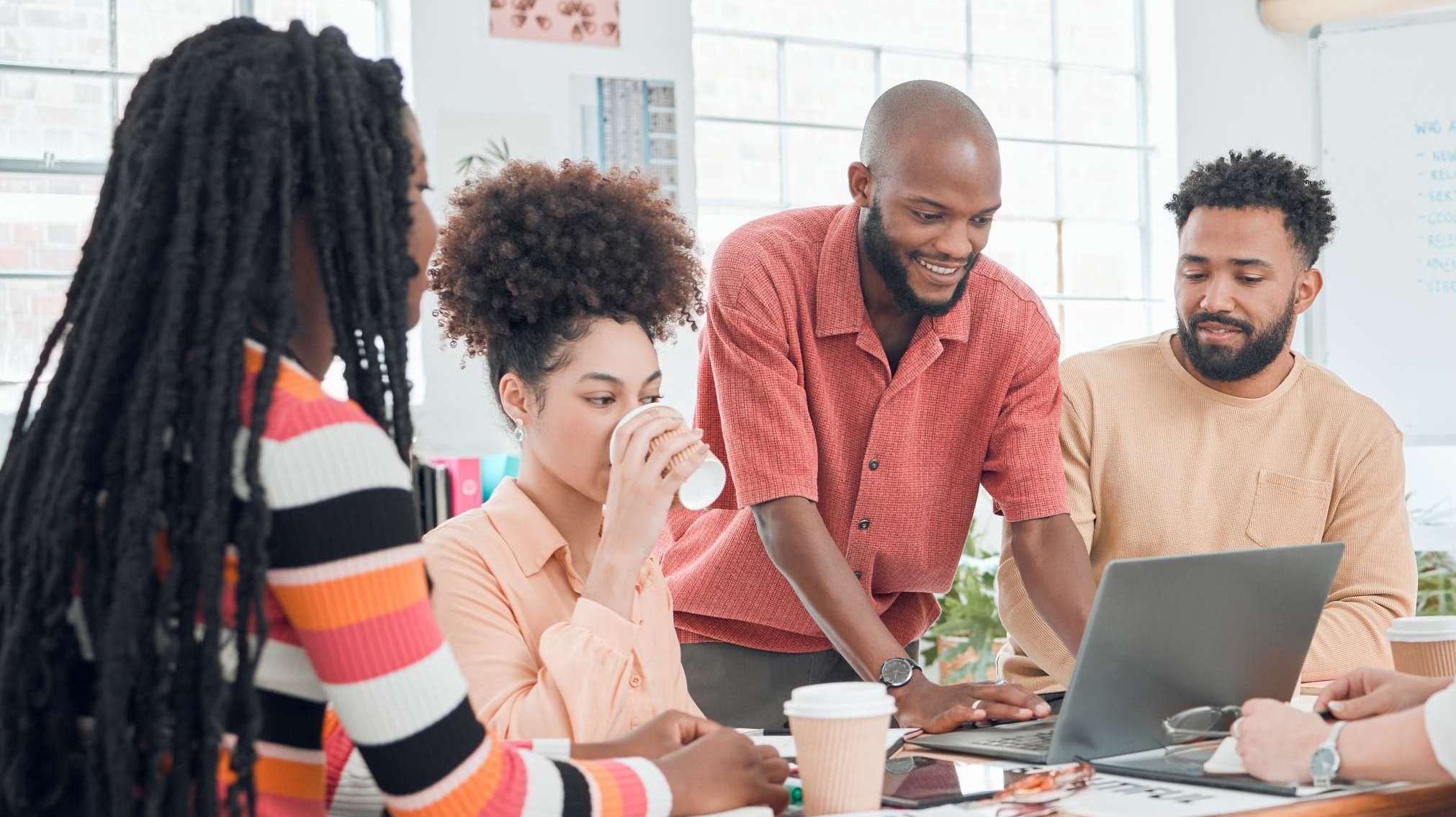 Group of young professionals collaborating around a laptop in a creative meeting