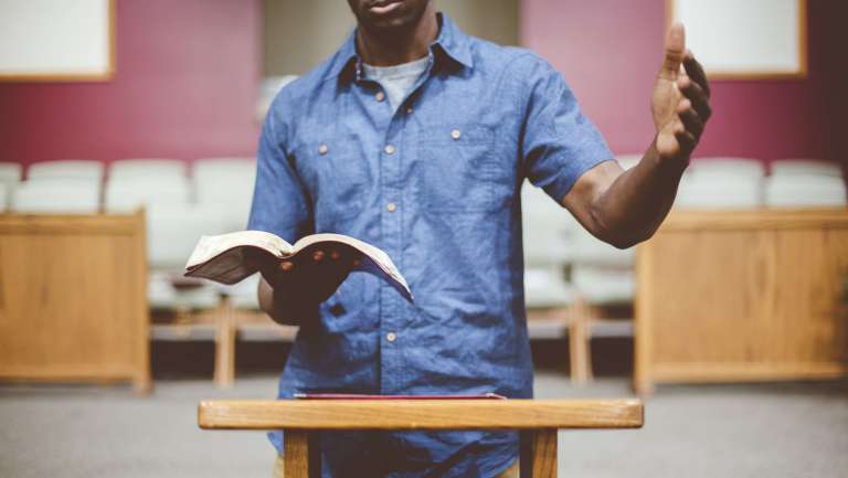 Pastor preaching from the Bible at a pulpit, emphasizing effective church communication and message delivery.