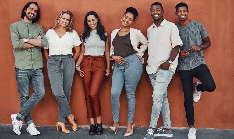 A diverse group of smiling young adults standing together, representing Millennials and Gen Z in church community.