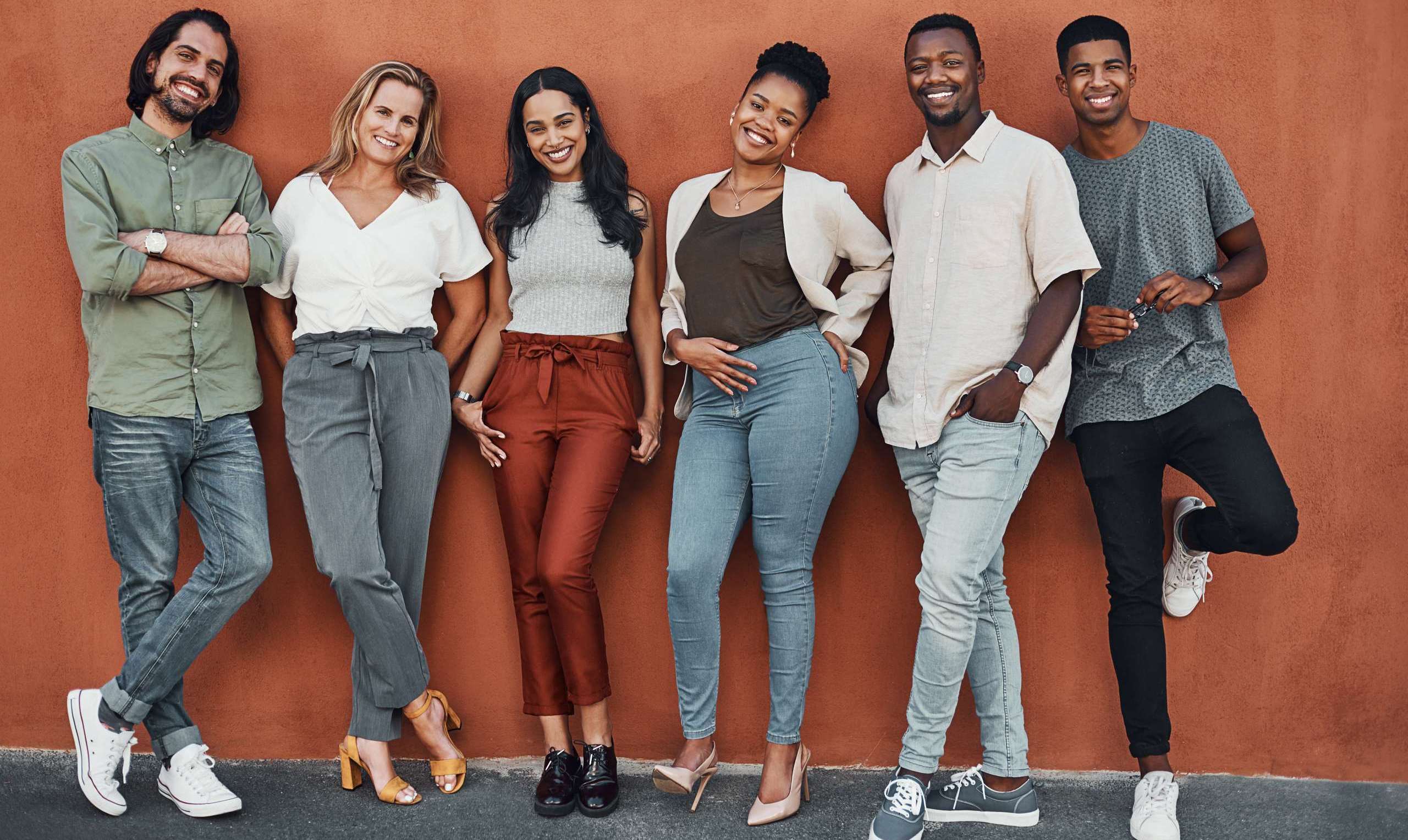 A diverse group of smiling young adults standing together, representing Millennials and Gen Z in church community.