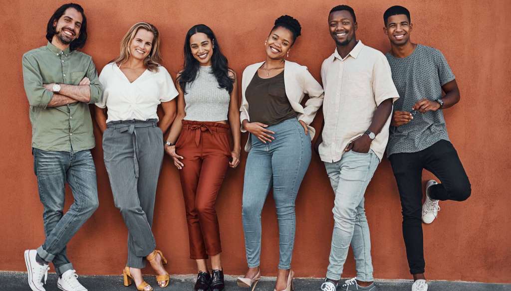 A diverse group of smiling young adults standing together, representing Millennials and Gen Z in church community.