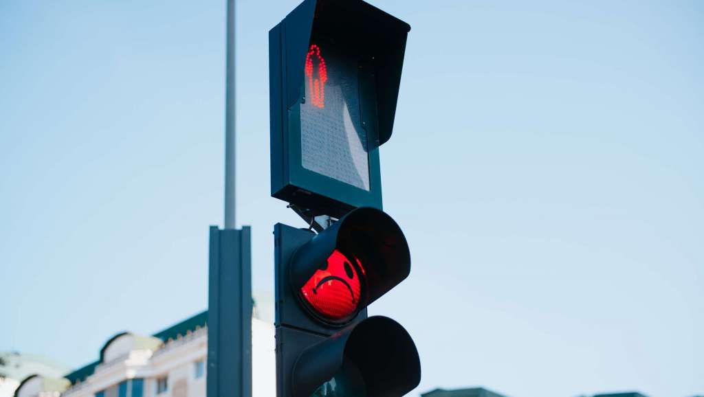 Close-up of a glowing red pedestrian traffic light and stop sign in an urban area during daylight