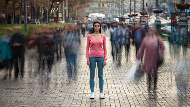 Woman standing still in a fast-moving crowd, representing the importance of identifying and connecting with your target audience.