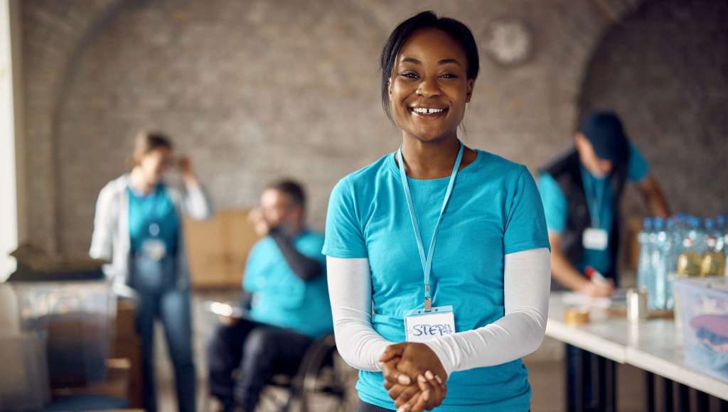 Smiling African American woman volunteering at a community event, symbolizing motivation and purpose in church engagement.