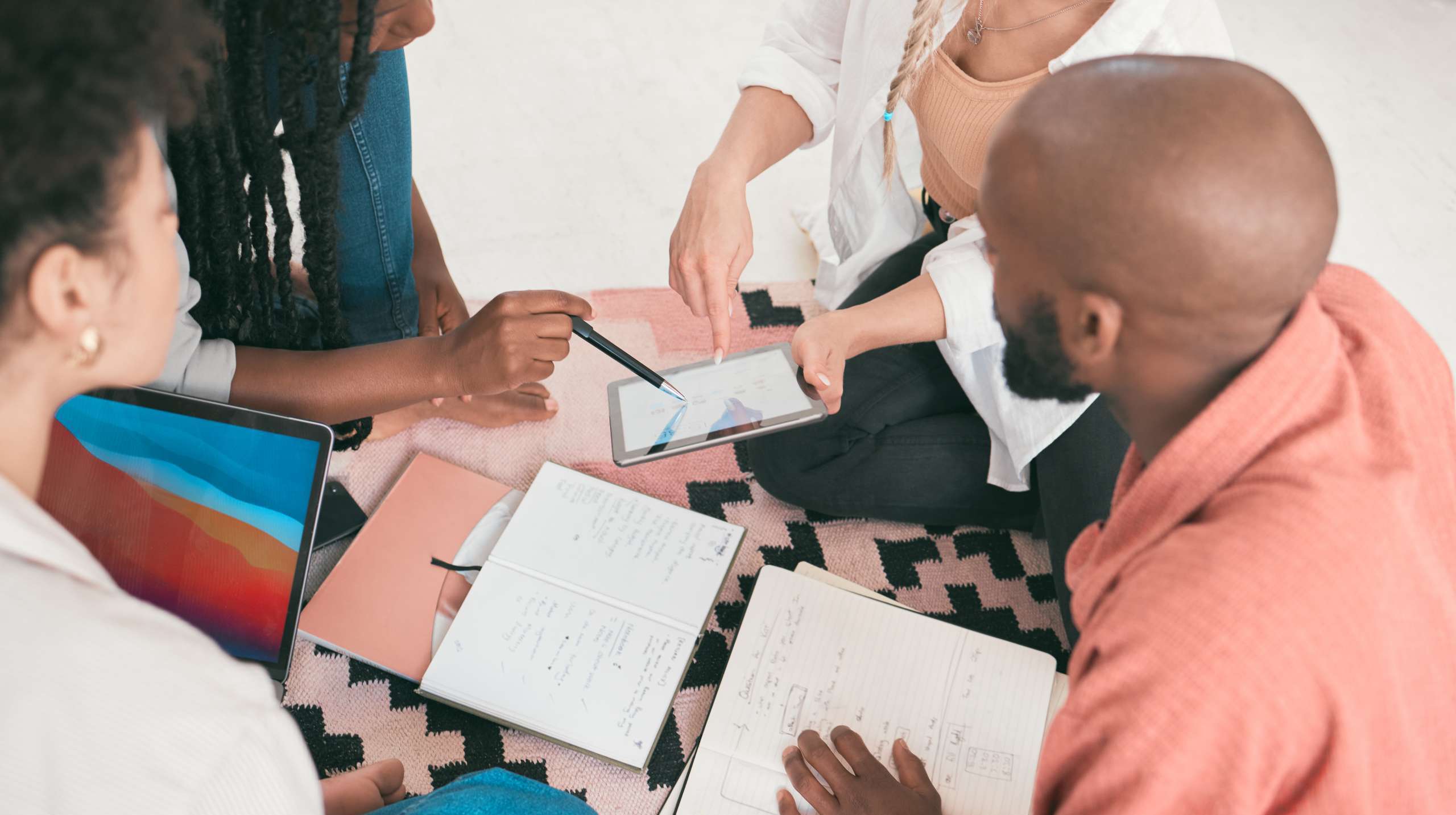 A diverse group of church team members sitting together with notebooks and a tablet, planning their communication and marketing strategy in a relaxed, collaborative setting.