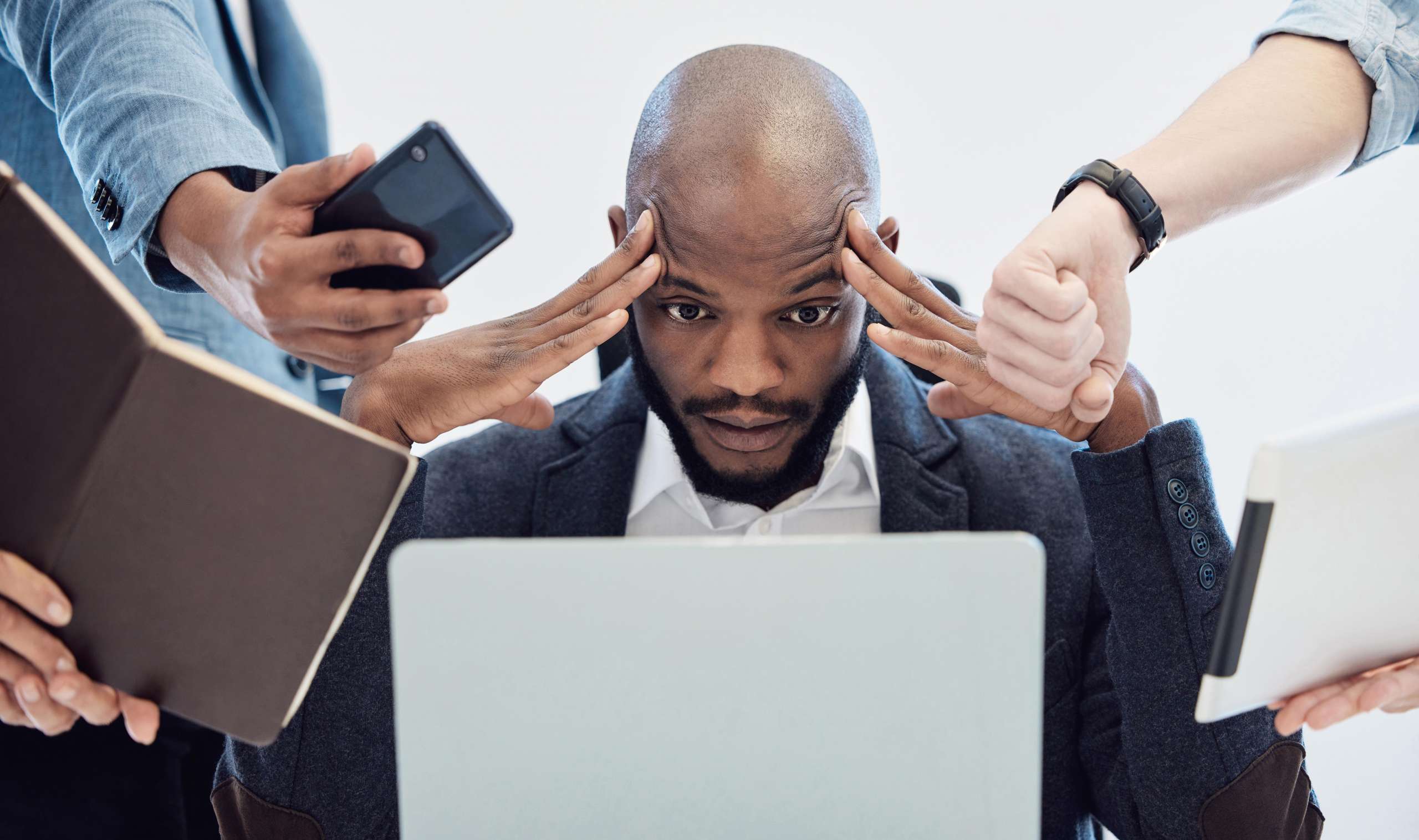 A church leader sits at a desk looking overwhelmed as multiple people hand him devices and papers, symbolizing communication overload and lack of focus.