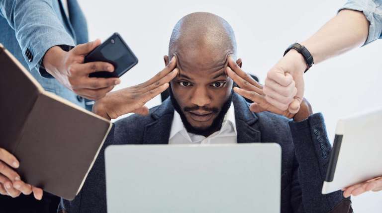 A church leader sits at a desk looking overwhelmed as multiple people hand him devices and papers, symbolizing communication overload and lack of focus.