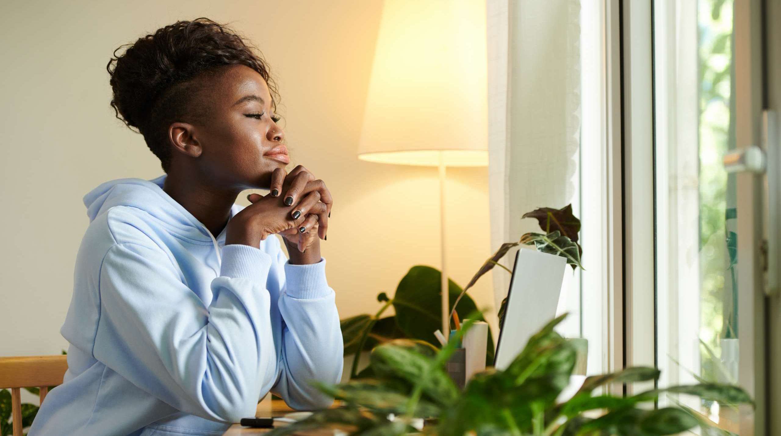 Woman sitting thoughtfully at a desk reflecting after finishing a major goal and considering what comes next